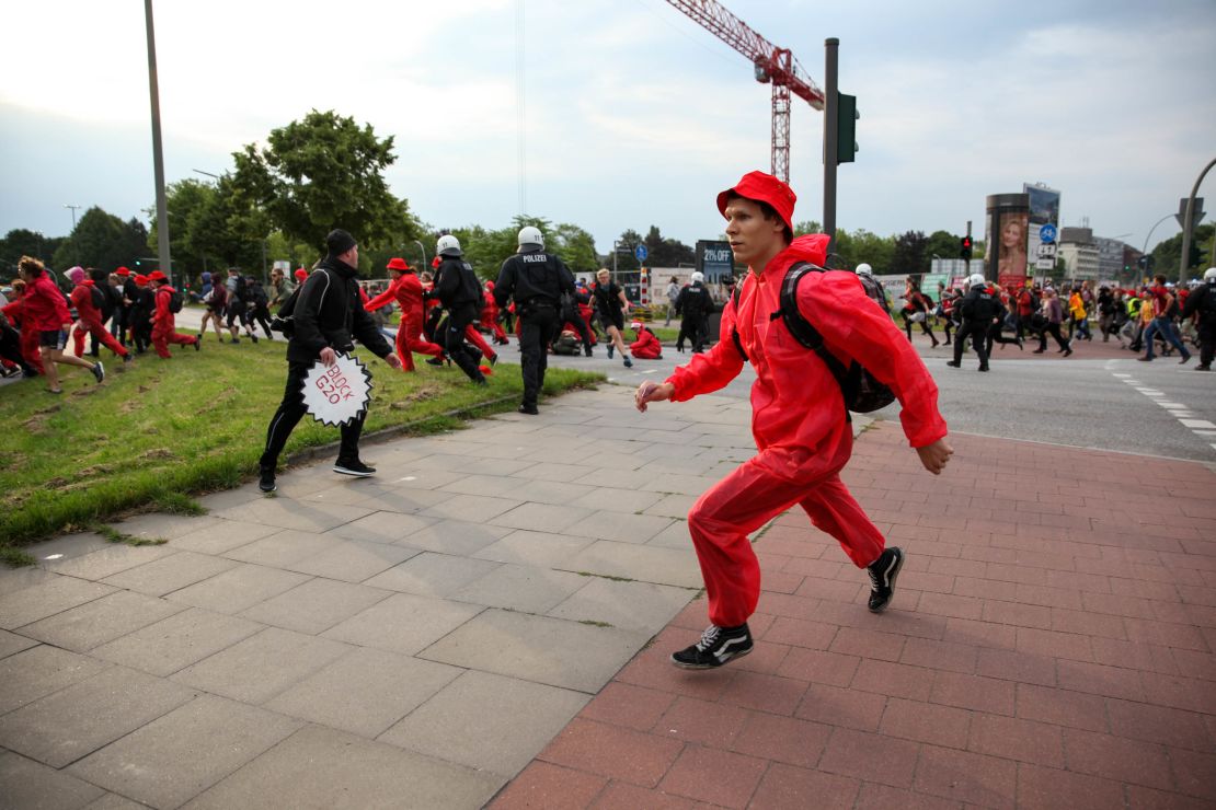 Protestors attempting to cross through the "Red Zone" barrier are chased by riot police on Friday.