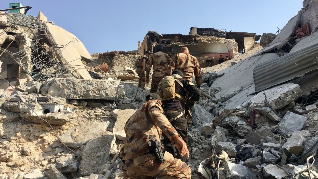 Counter-Terrorism Service (CTS) troops climb a mound of rubble.