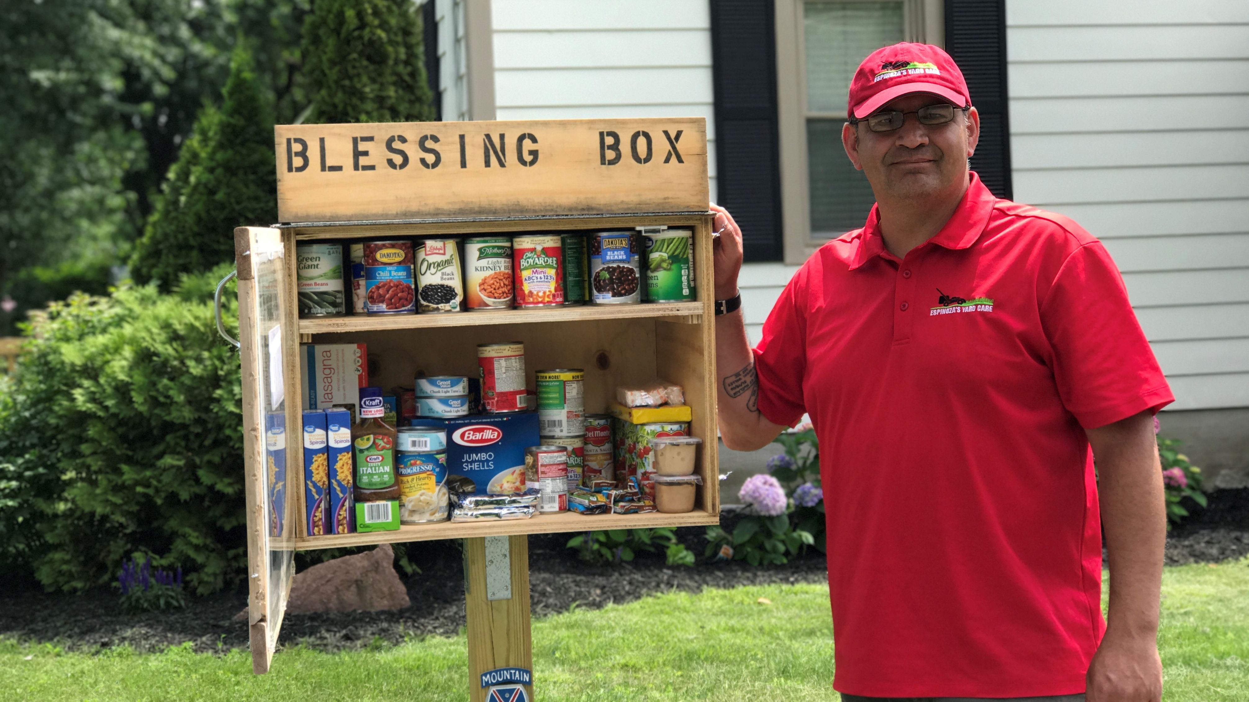 Roman Espinoza stands beside his "Blessing Box," which allows residents of Watertown, New York, to donate and take food as needed. 