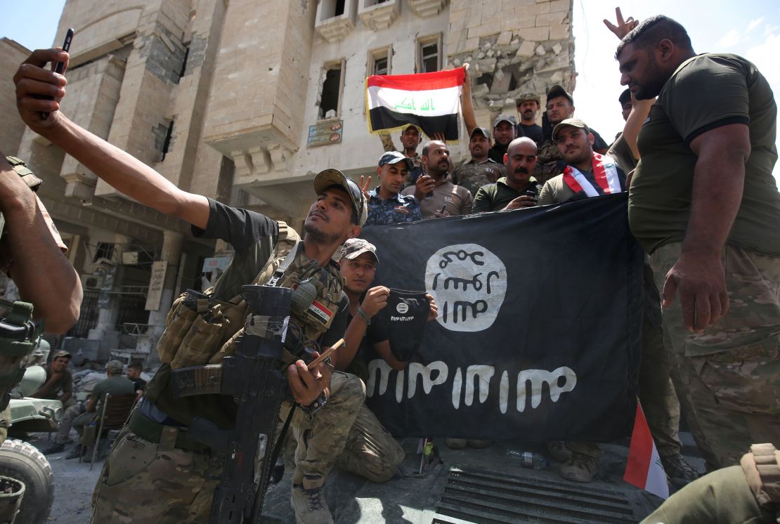 Iraqi troops pose with an upside down ISIS flag in Mosul on July 8.
