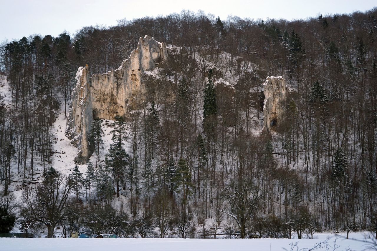 The Geißenklösterle cave is located along the southern ridge of a large rock massif, the Bruckfelsen, about 60 meters above the Ach River. The cave entrance is located on the southern edge of a rock formation that was originally a large cave hall which is thought to have collapsed during the ice age. 