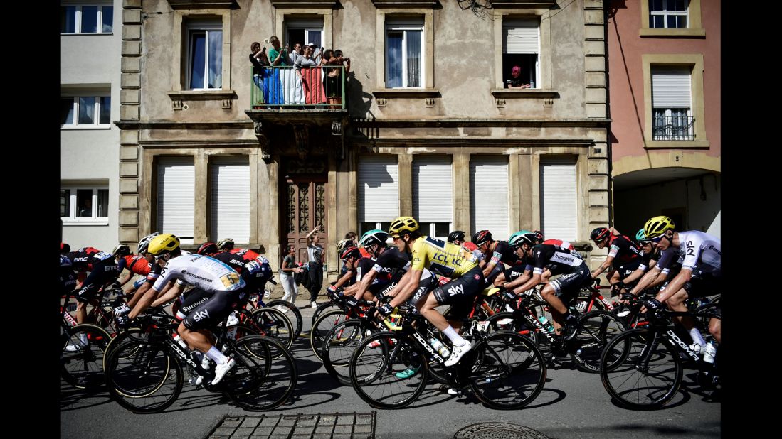 Great Britain's Geraint Thomas (C) wearing the overall leader's yellow jersey rides in the pack past supporters during the 212,5 km third stage. The Welshman won the leader's jersey after victory in the first stage and held onto it until the fifth, when teammate Chris Froome surged into the overall lead. However,  Thomas had to withdraw from the race after breaking his collarbone on the tough Col de la Biche descent on stage nine.