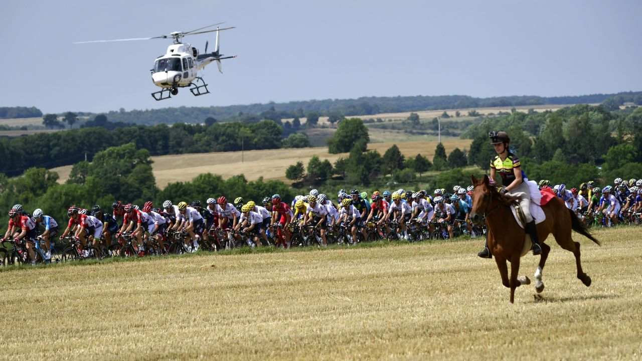A horse rider is pictured in front of the pack as a media helicopter flies overhead during the seventh stage between Troyes and Nuits-Saint-Georges.