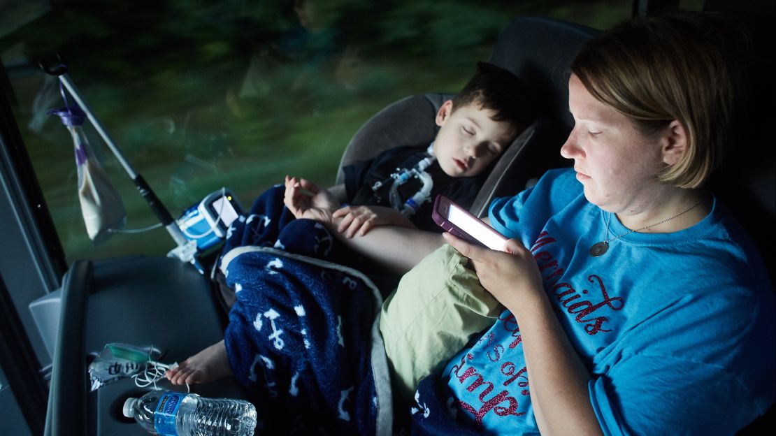 Gabe Michot, 4, holds his mother's arm as he sleeps on the bus.
