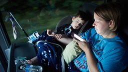 Gabe Michot, 4, holds his mother's arm as he sleeps on a bus ride from Baton Rogue to Washington DC on Sunday, July 9, 2017 in Raleigh, NC. Jessica Michot says Gabe was born premature and has several health issues including using a tracheostomy tube to breathe.   Photo by John Nowak/CNN