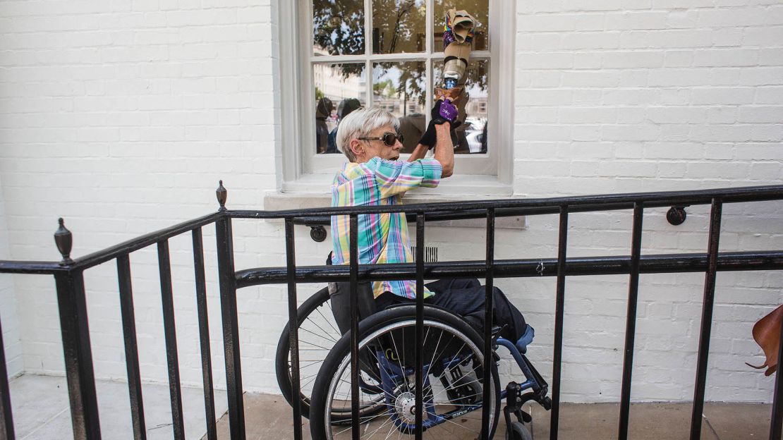 Becky Ogle knocks on a window of the Republican National Commitee headquarters with her prosthetic leg as she protests proposed cuts to Medicaid.