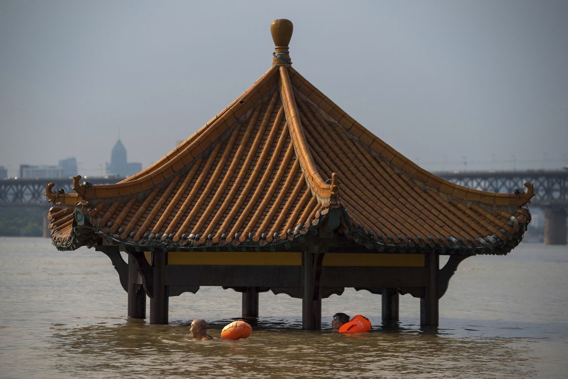 People swim past the top of a pagoda at a flooded riverside park in Wuhan on Monday, July 3.