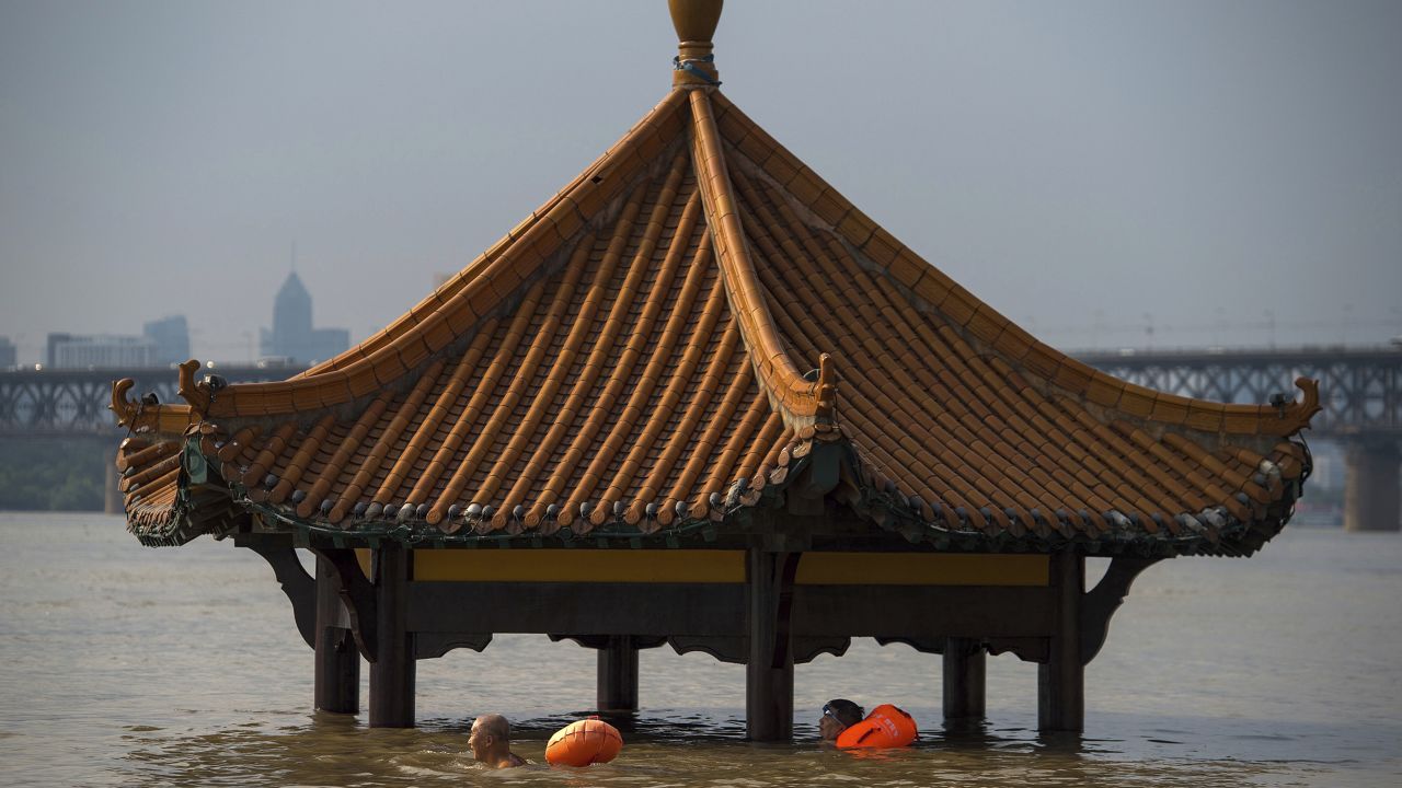 People swim past the top of a pagoda at a flooded riverside park in Wuhan on Monday, July 3.