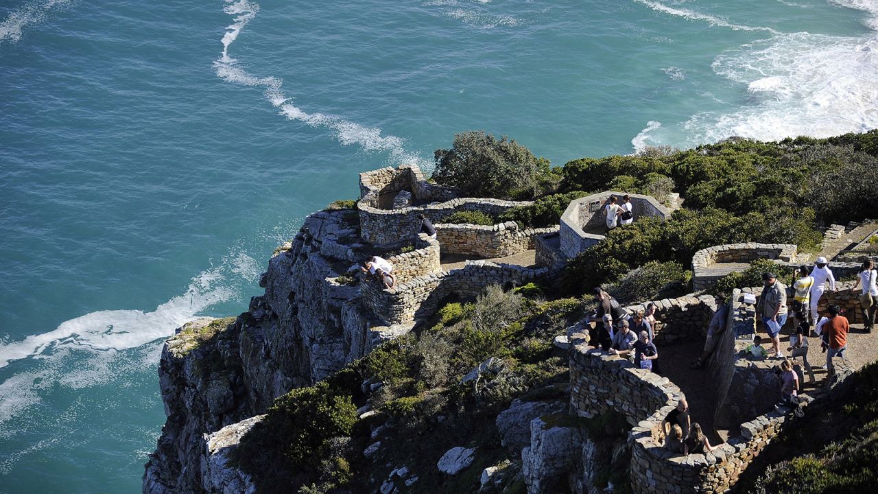 Tourists enjoy the view from Cape Point on May 8, 2010 on the southern tip of the Cape Peninsula, some 50 kms south of Cape Town, South Africa. When following the African coastline from the equator the Cape of Good Hope marks the psychologically important point where one begins to travel more eastward than southward. Thus the first rounding of the cape in 1488 by Portuguese explorer Bartolomeu Dias was a major milestone in the attempts by the Portuguese to establish direct trade relations with the Far East. He called the cape Cabo Tormentoso. As one of the great capes of the South Atlantic Ocean, the Cape of Good Hope has been of special significance to sailors for many years and is widely referred to by them simply as "the Cape". It is a major milestone on the clipper route followed by clipper ships to the Far East and Australia, and still followed by several offshore yacht races. AFP PHOTO/GIANLUIGI GUERCIA (Photo credit should read GIANLUIGI GUERCIA/AFP/Getty Images)