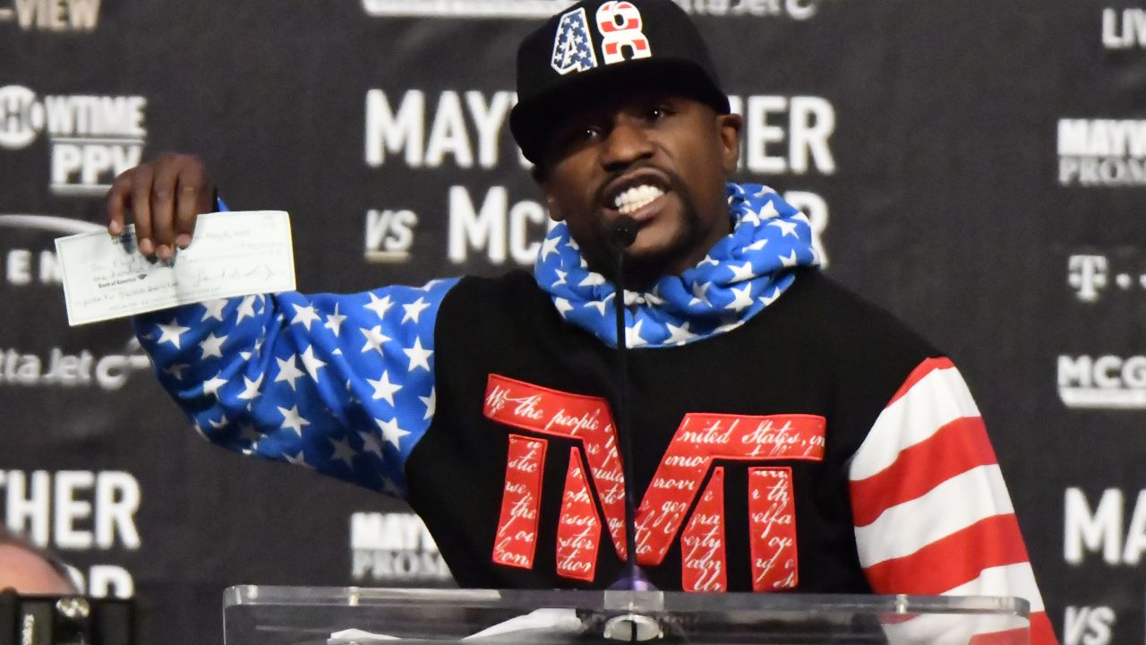 Floyd Mayweather Jr. holds up a check ahead of his August fight with Conor McGregor.