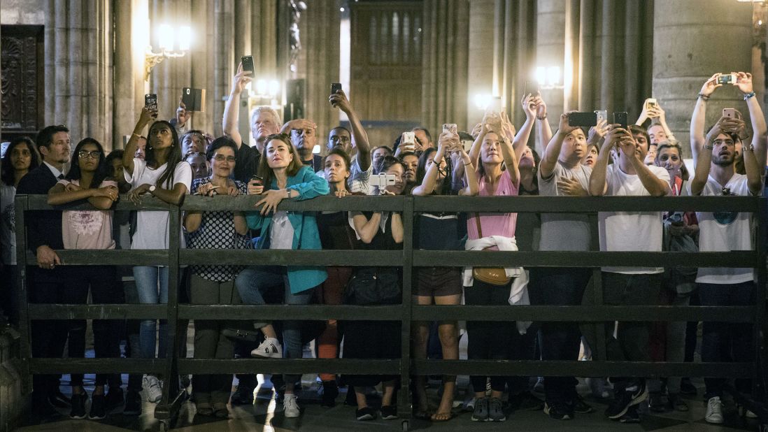 Tourists take pictures of Melania Trump as she visits the Notre Dame Cathedral on July 13.