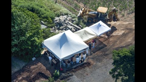Investigators gather under tents as they search a property in Solebury for four missing men.