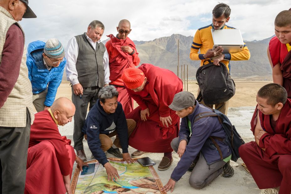 Sonam Wangchuk shows building plans to monks and colleagues at the planned site for a university.
