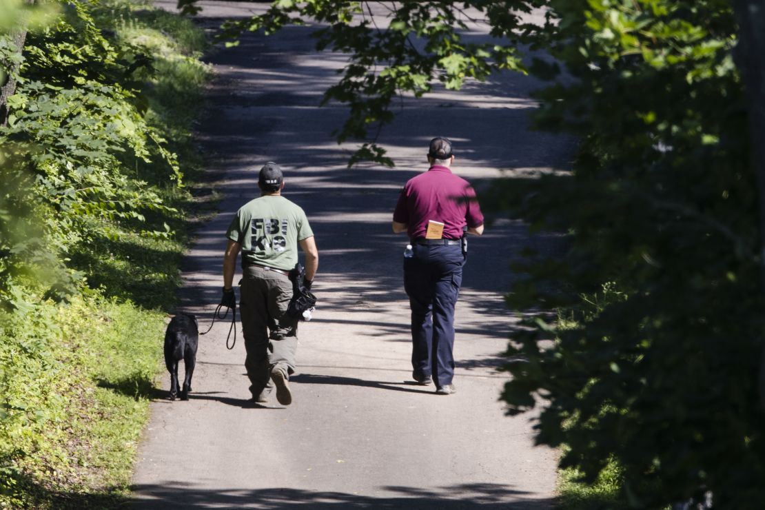 Investigators and a dog walk up a driveway amid the search for four missing young Pennsylvania men.