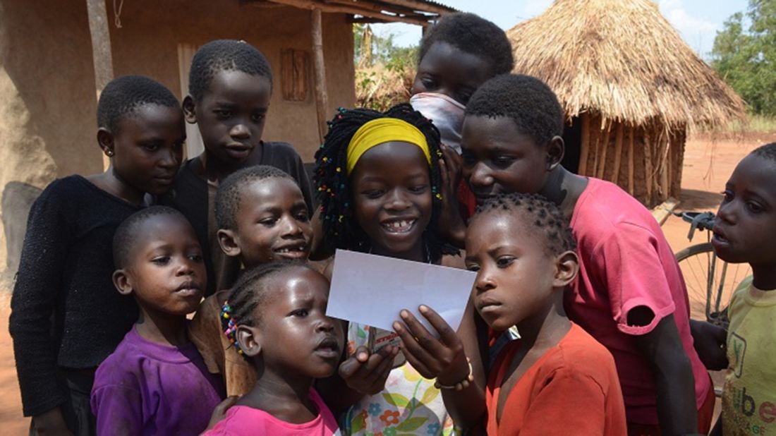 Mata, as she's known, shows village children a photo of her playing in the snow while she lived with the Davises in Ohio. <br />