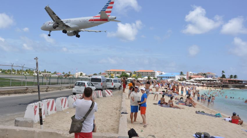 A plane lands at the Princess Juliana International Airport as beachgoers watch in Philipsburg, St. Maarten, a Dutch Caribbean territory, Thursday, July 13, 2017. On Wednesday, a New Zealand tourist was killed by the blast from a jetliner taking off when she was knocked into a wall as she tried to cling to a fence to feel the blast. (AP Photo/Judy Fitzpatrick)
