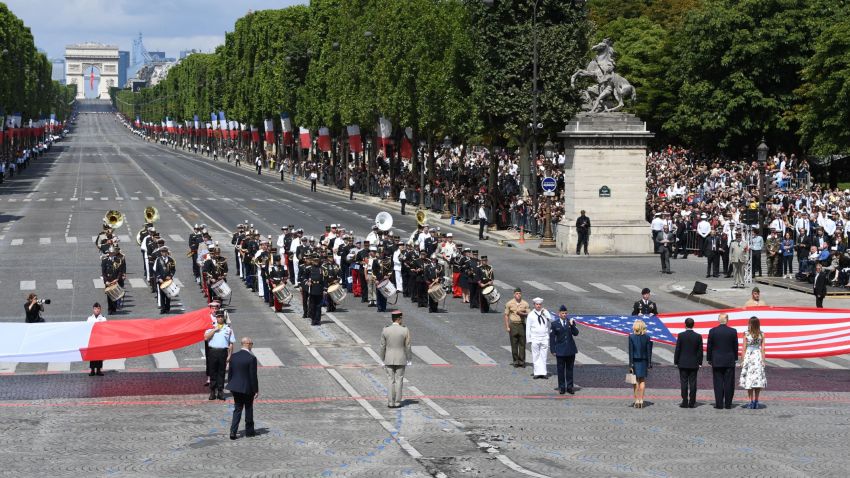 (RtoL) US First Lady Melania Trump, US President Donald Trump, French President Emmanuel Macron and his wife Brigitte Macron, walk towards the US national flag held by soldiers, as a French joint-army brass band performs, at the end of the annual Bastille Day military parade on the Champs-Elysees avenue in Paris on July 14, 2017.  
The parade on Paris's Champs-Elysees will commemorate the centenary of the US entering WWI and will feature horses, helicopters, planes and troops. / AFP PHOTO / ALAIN JOCARD        (Photo credit should read ALAIN JOCARD/AFP/Getty Images)