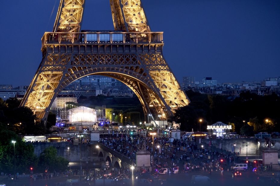 A crowd gathers outside a police cordon below the Eiffel Tower as the two leaders and their wives attend a dinner at Le Jules Verne restaurant on Thursday, July 13.