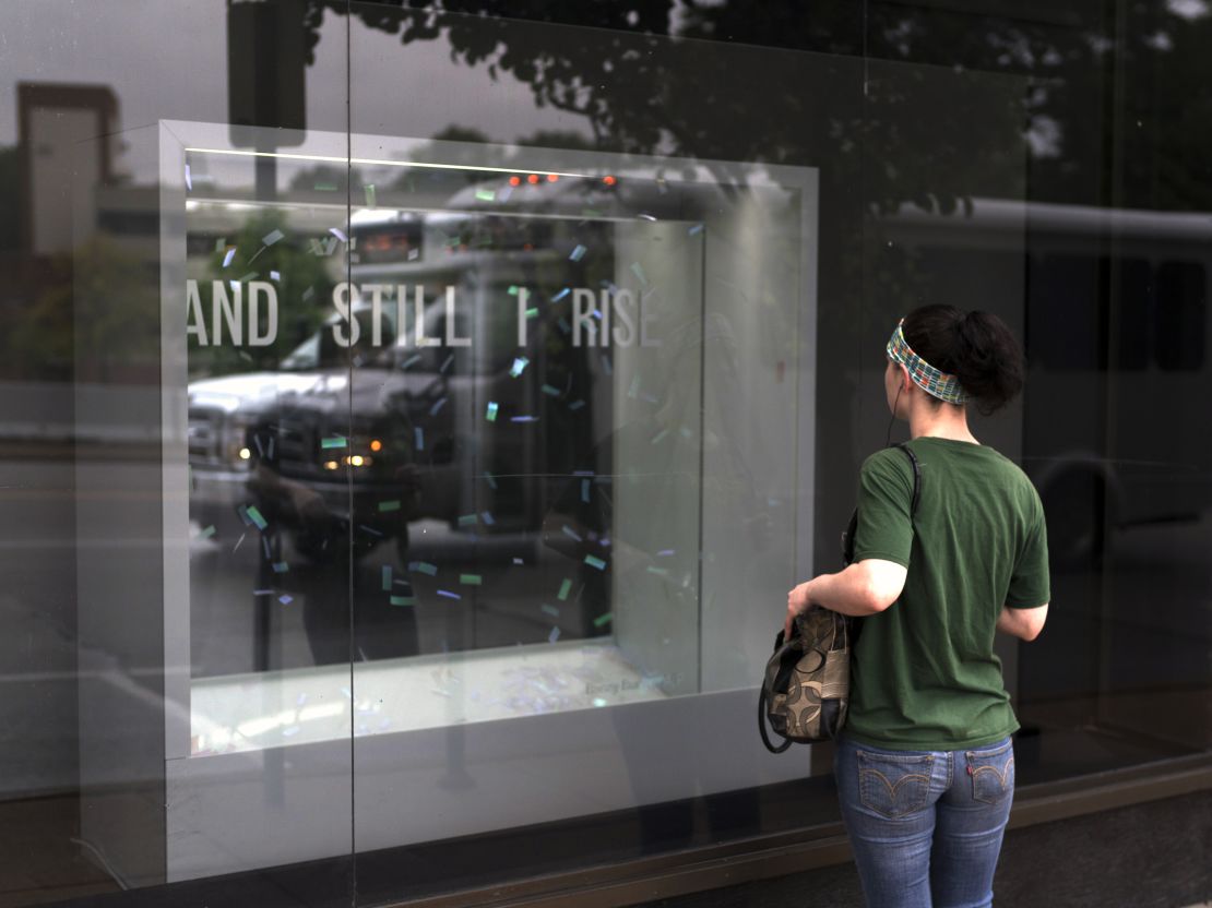 A woman watches the "And Still I Rise" exhibit from outside the Bruno David Gallery in St. Louis.