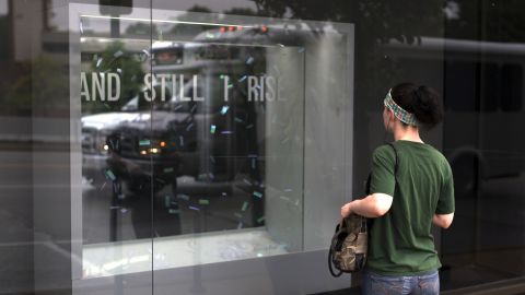 A woman watches the "And Still I Rise" exhibit from outside the Bruno David Gallery in St. Louis.