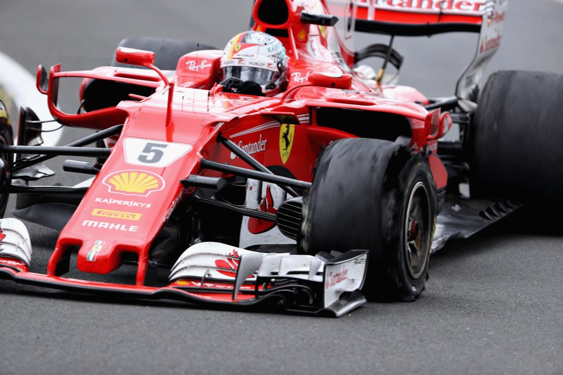 Sebastian Vettel drives his Ferrari with a puncture clearly noticeable on his shredded front left tire.