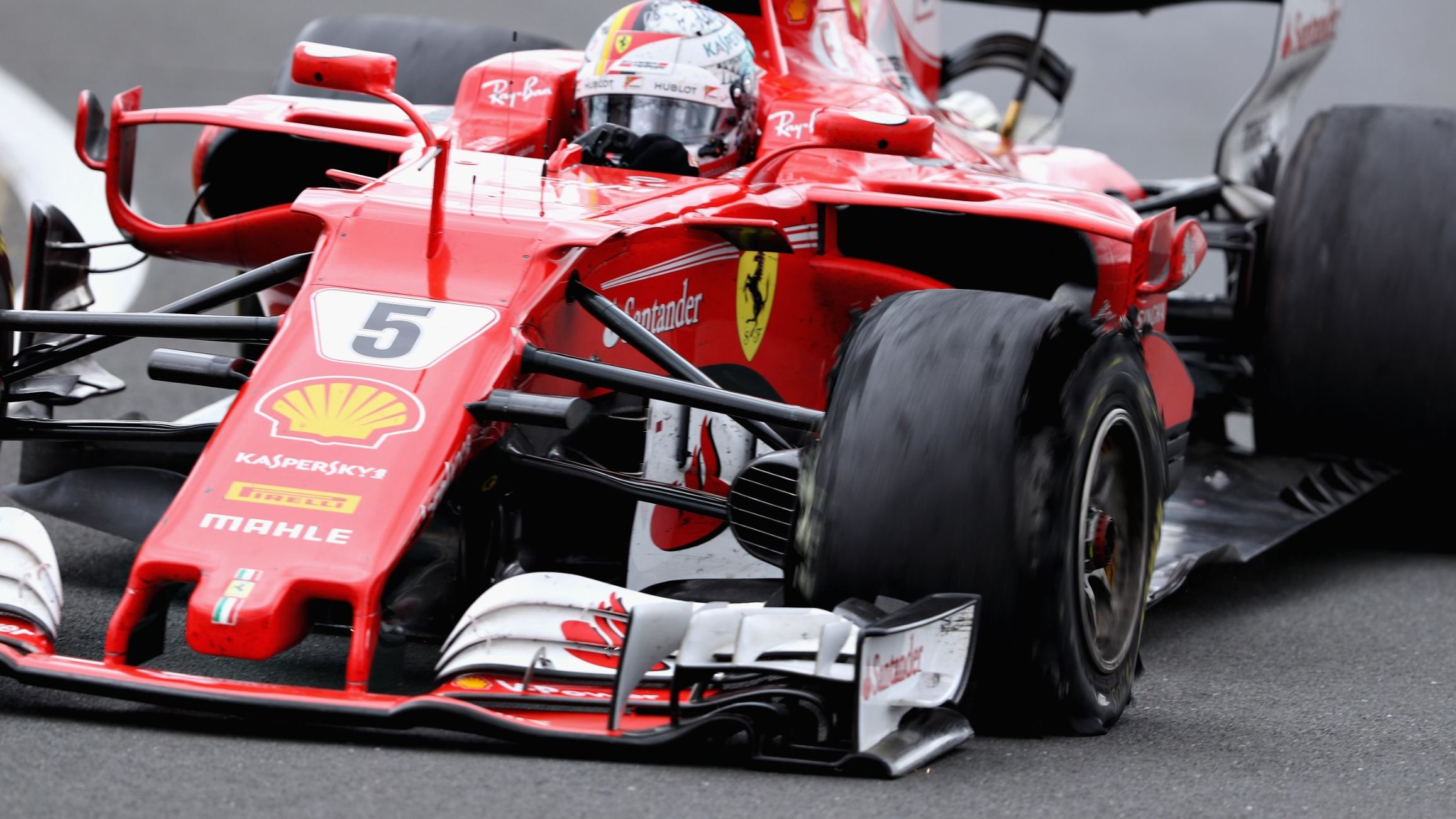 Sebastian Vettel drives his Ferrari with a puncture clearly noticeable on his shredded front left tire.