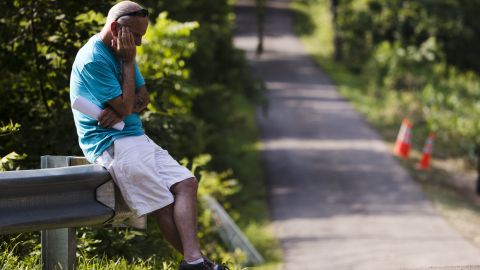 A man sits at the end of driveway in Solebury, as the search continues for four missing young men feared to be the victims of foul play.