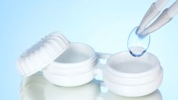 contact lenses in containers and tweezers on blue background; Shutterstock ID 117754834; PO: CNN Photos