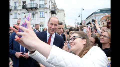 William poses for a selfie with a woman on July 17, as a crowd gathers outside the Presidential Palace in Warsaw, Poland, to greet the royals.