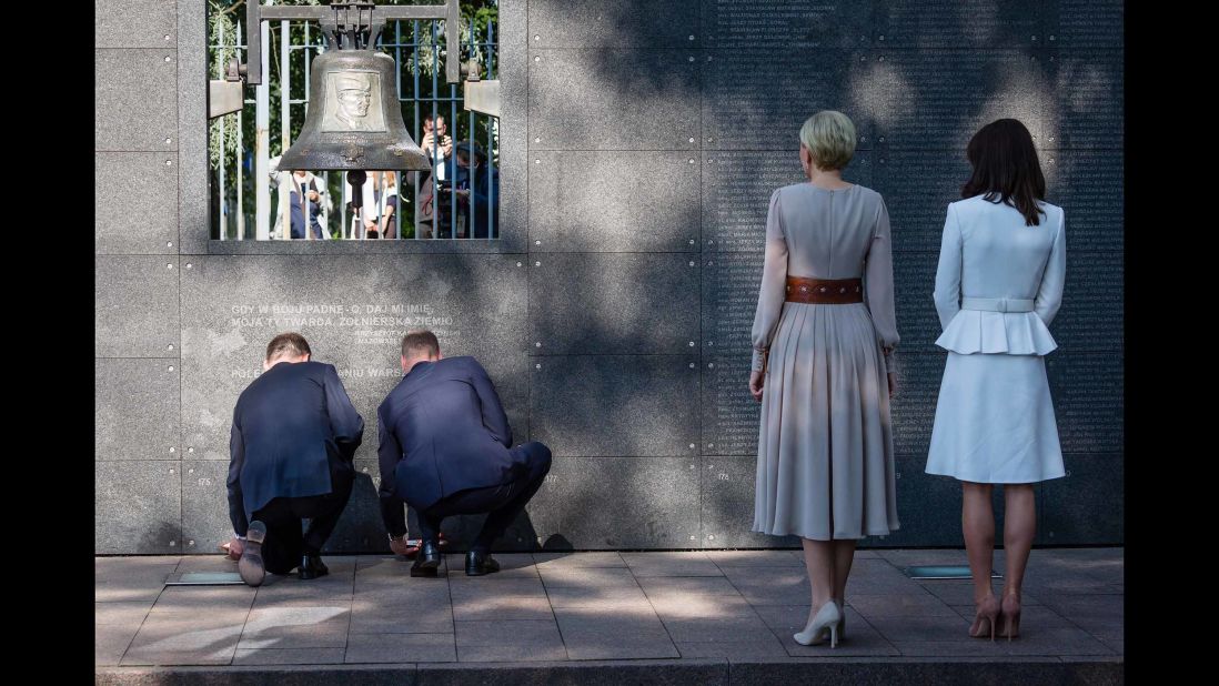 Duda, left, and William, kneel as they light candles during a visit to the Warsaw Uprising Museum while Poland's first lady, second from right, and Kate look on.