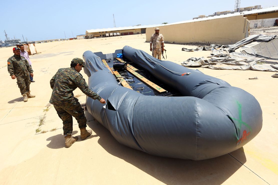 Libyan naval officers punctures a dinghy used by illegal migrants at the naval base in Tripoli on May 6.