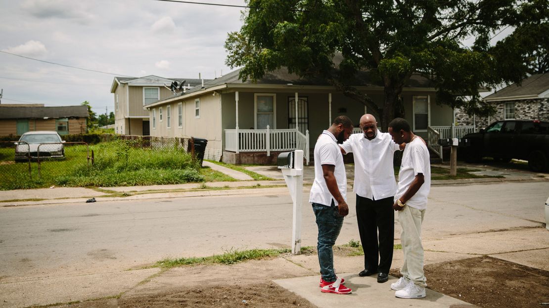 From left, La'Marque Victor, the Rev. Robert Brown and Derrick Scott pray in front of Victor's house. Brown works hard to rally people to tackle issues in the Goose because "the problem we have right now is galvanizing people," he says.