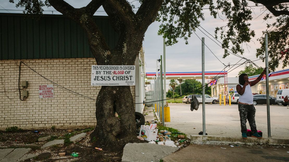A sign welcoming people into the Goose reads, "This neighborhood is covered by the blood of Jesus Christ." In the background is the Discount Zone gas station where several shootings have occurred in recent years. 