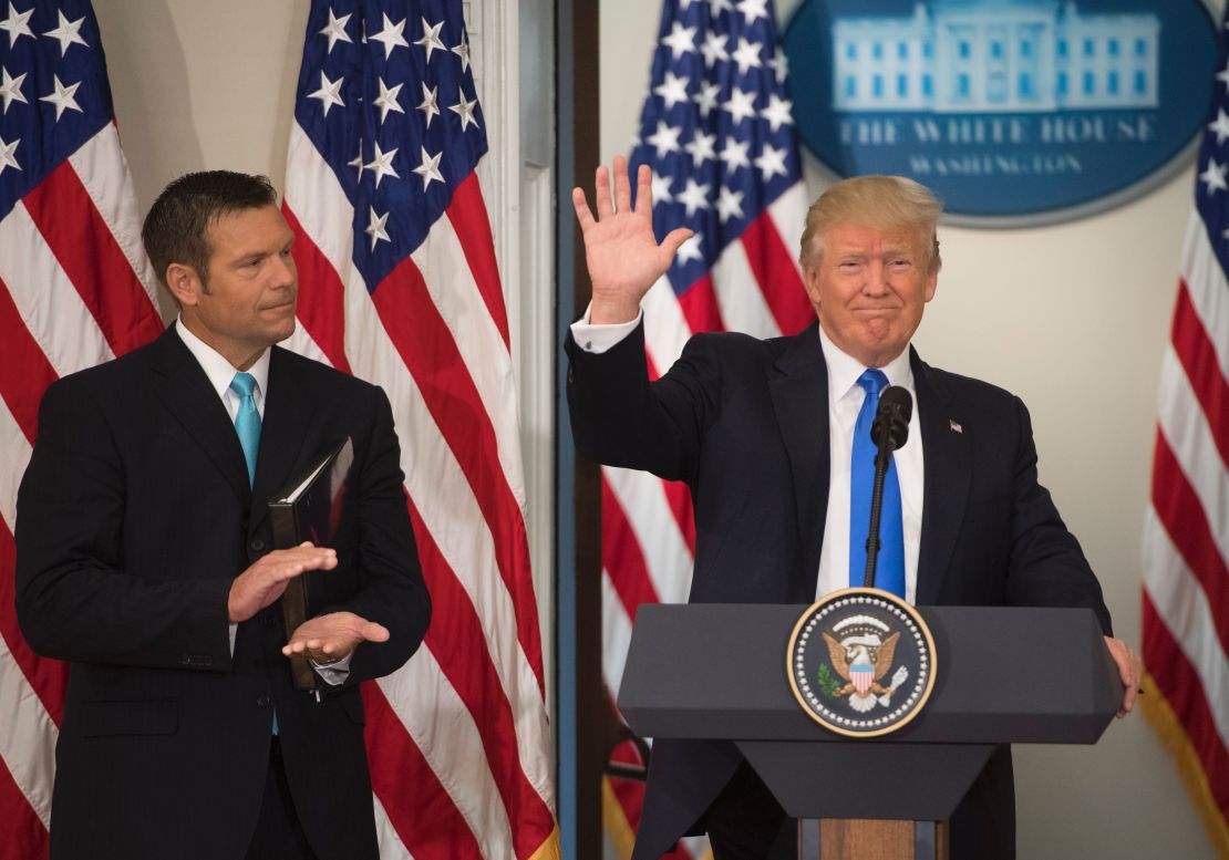 President Donald Trump waves after speaking alongside then-Kansas Secretary of State Kris Kobach in the Eisenhower Executive Office Building next to the White House in July 2017.