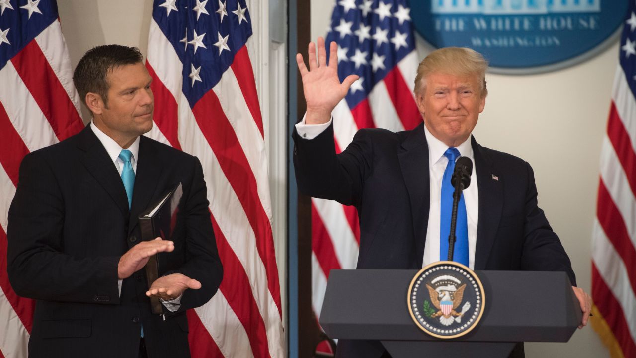 President Donald Trump waves after speaking alongside then-Kansas Secretary of State Kris Kobach in the Eisenhower Executive Office Building next to the White House in July 2017.