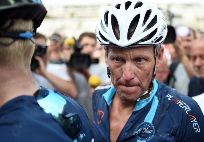 US cyclist Lance Armstrong looks on upon his arrival in Rodez, southwest France, after riding a stage  of The Tour De France for a leukaemia charity, a day ahead of the competing riders, on July 16, 2015. For the first time since he was stripped of his seven Tour de France titles, disgraced cyclist Lance Armstrong rode a stage of the famous race for charity. Armstrong, 43, was riding a 198-kilometre (123-mile) stage a day ahead of the competing riders for a leukaemia charity but cycling officials have branded the exercise