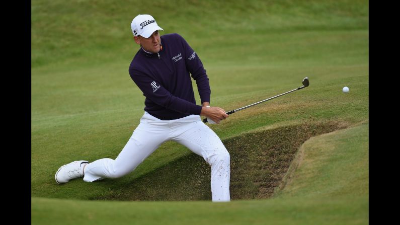 Ian Poulter of England plays out of a bunker on the seventh hole.