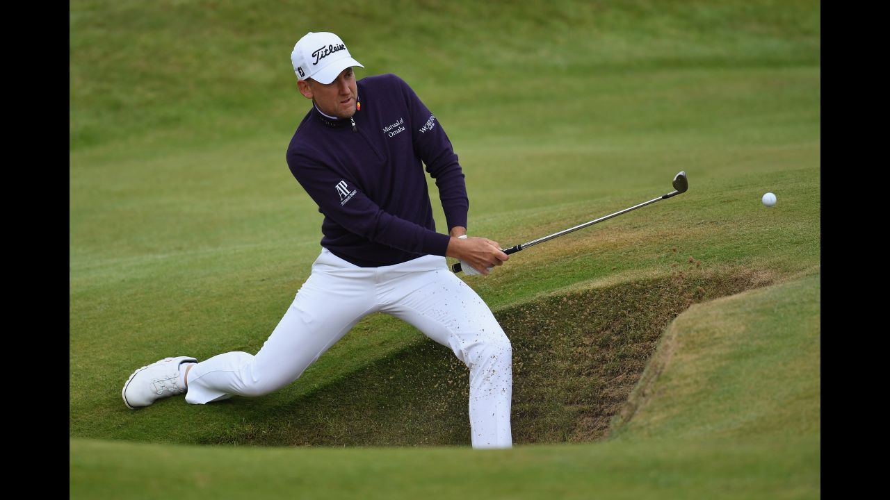 Ian Poulter of England plays out of a bunker on the seventh hole.  