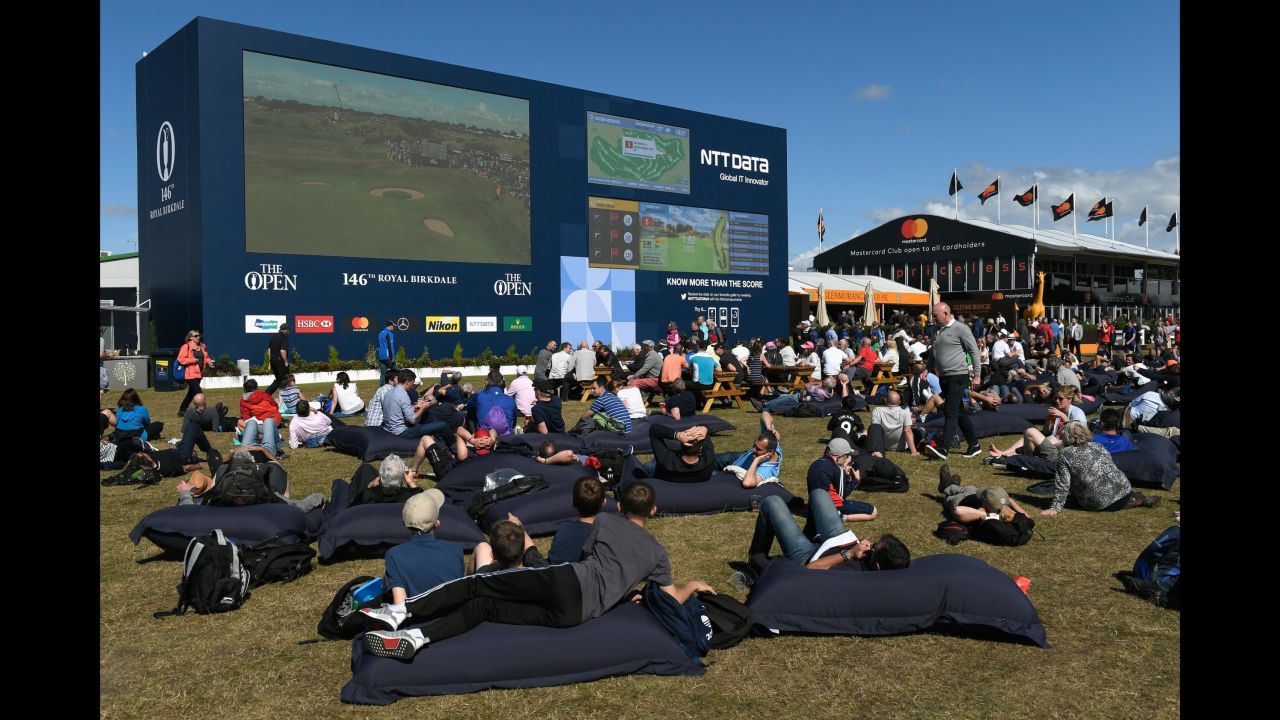 Golf fans on giant beanbags watch the action on a big screen in the spectator village.