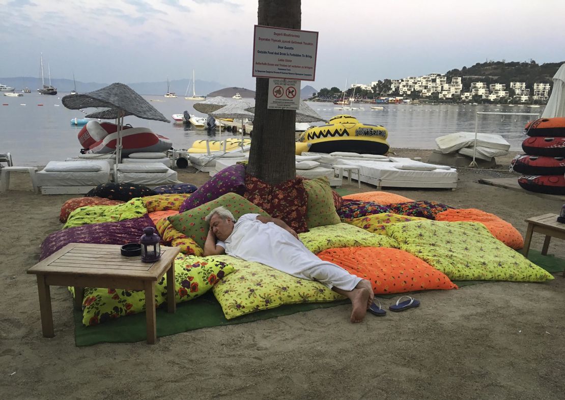A man in Bitez, a resort town west of Bodrum in Turkey sleeps on the beachfront following the earthquake in the early hours of Friday morning.
