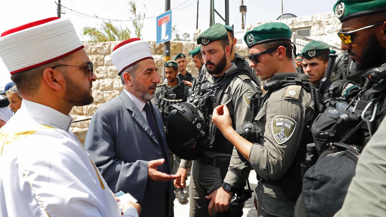 Muslim clerics speak with Israeli border guard last week outside the Lions' Gate in Jerusalem's Old City.