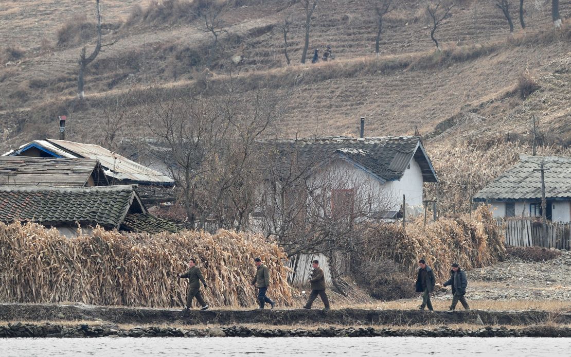 North Korean men walk amid a dry and barren landscape on the banks of the Yalu River in November 2010.