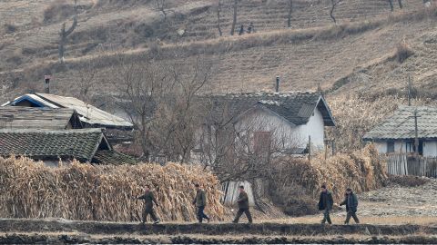 North Korean men walk amid a dry and barren landscape on the banks of the Yalu River in November 2010.
