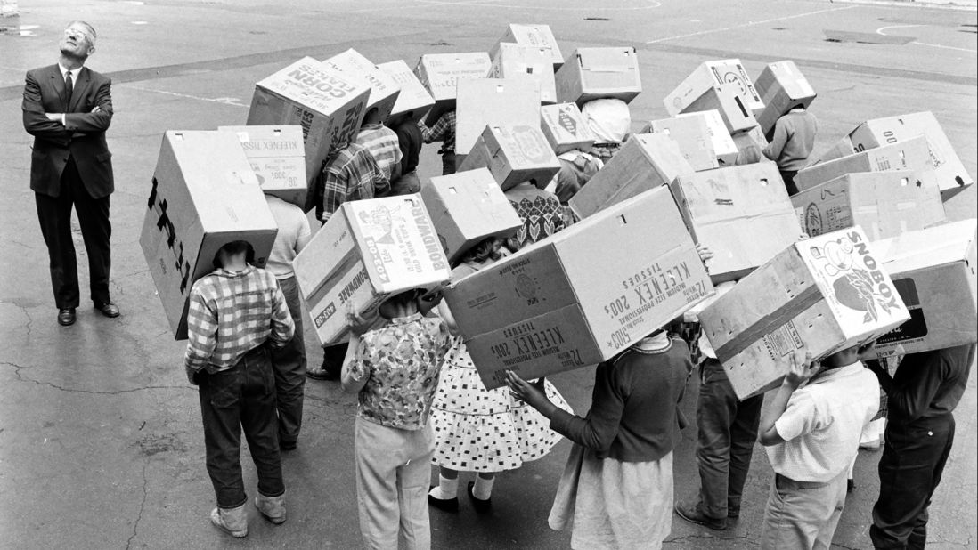 5th grade students from Emerson Elementary School with "sunscopes" (cardboard boxes) over their heads, used to view a solar eclipse without harming their eyes in Maywood, Illinois, 1963. 