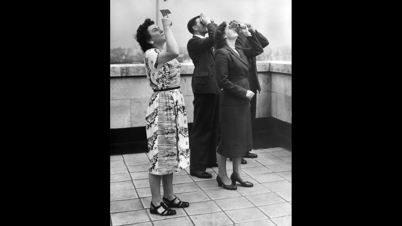 Office workers view the eclipse of the sun from the roof of Shell Mex House in London in June 1954.  
