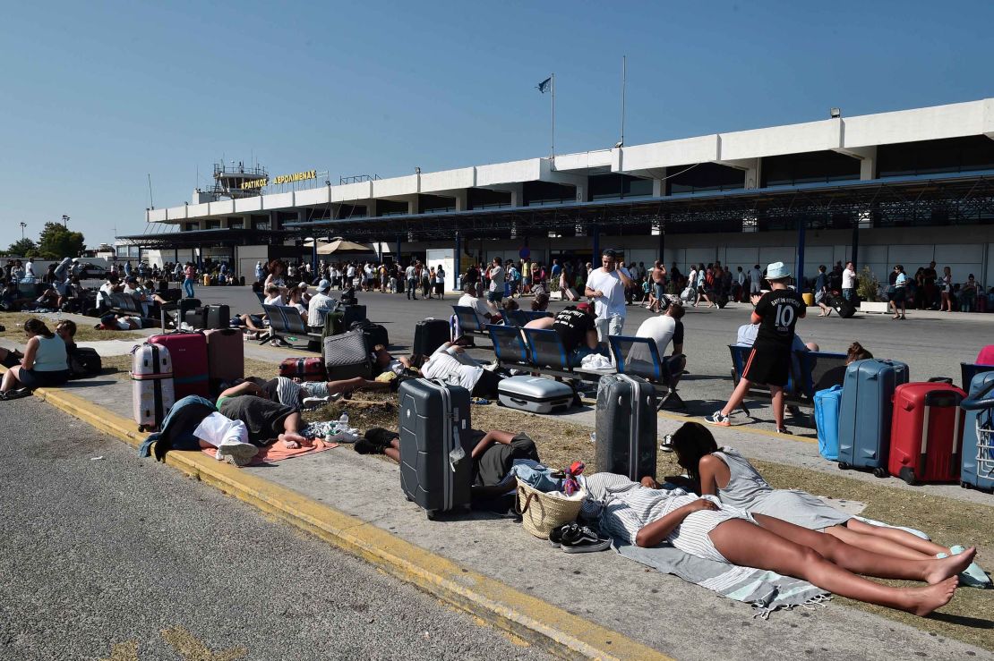 Tourists wait outside the terminal at the airport on Kos. 