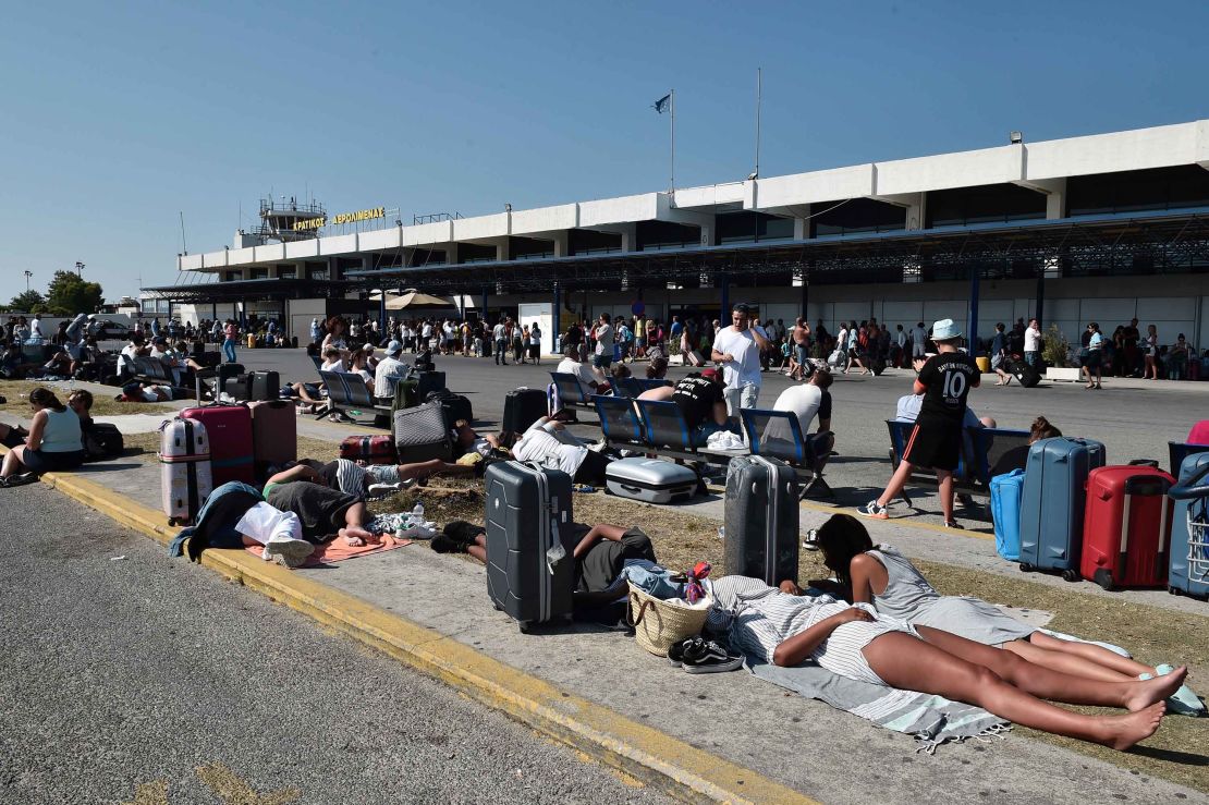 Tourists wait outside the terminal at the airport on Kos.