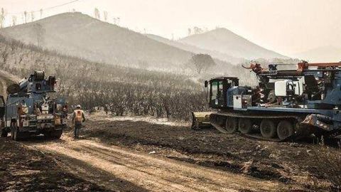 A crew Thursday morning works to replace power transmission poles that were destroyed by the Detwiler Fire near Mariposa.