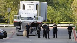 San Antonio police officers investigate the scene Sunday, July 23, 2017, where eight people were found dead in a tractor-trailer loaded with at least 30 others outside a Walmart store in stifling summer heat in what police are calling a horrific human trafficking case,  in San Antonio. 