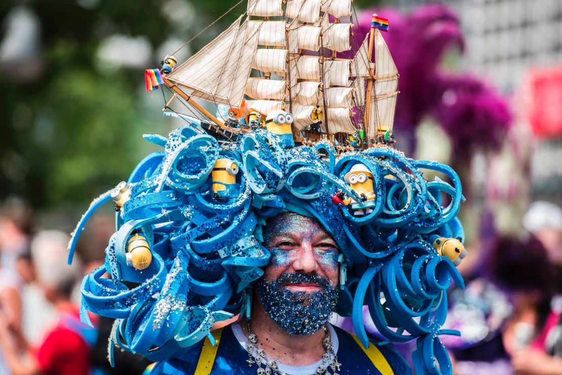 A man wears an intricate headpiece featuring a model ship and minions. 